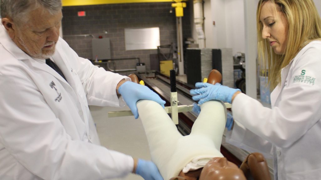 McLaren orthopedic resident placing cast on a crash dummy