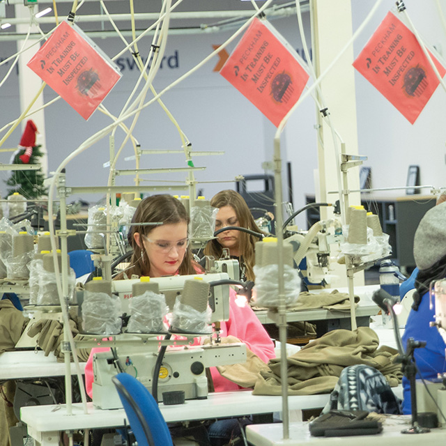 Production floor employee sewing garments at Peckham Inc.