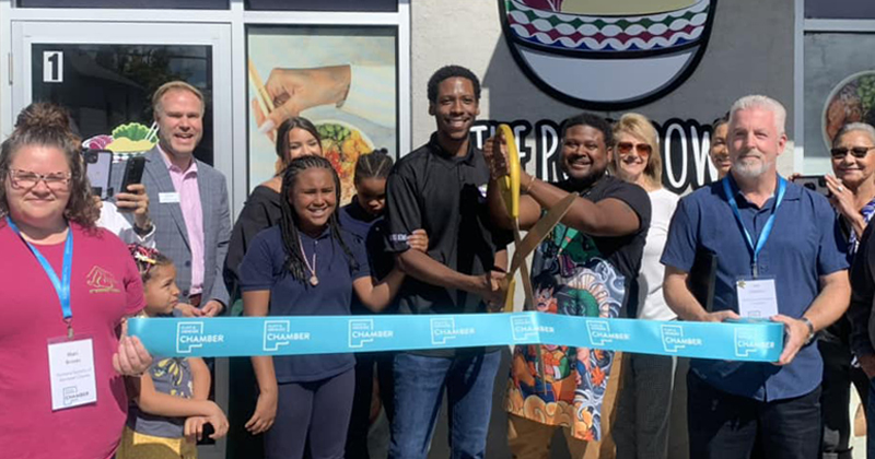 The owners and employees of The Poke Bowl cut a ribbon to open their new business with members of the Chamber assisting