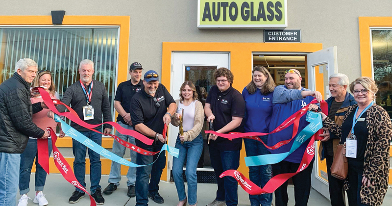 Employees and guests of Mr. Chip Windshield Repair line up and hold four ribbons printed with different organization's logos to cut the ribbon for a grand opening.