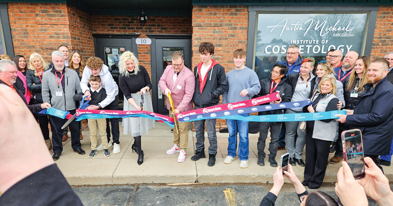 Owners, family and friends line up to cut three organization's ribbons for the grand opening of a beauty school.