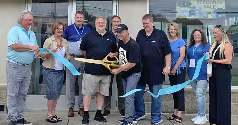 Staff and chamber members line up in front of a new store, Appliances 4 Less, for a ribbon cutting