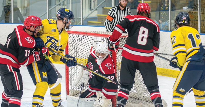 Hockey players from the University of Michigan-Flint try to move the hockey puck into the opposing team's goal.