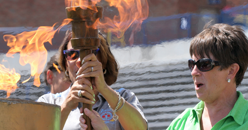 Two women prepare to light the torch with flames signaling the start of the CANUSA games. 