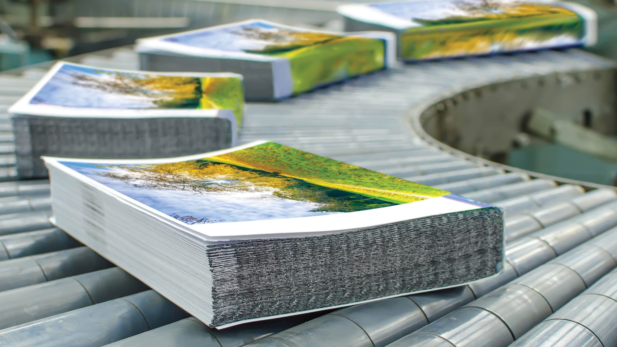 Stacks of printed booklets come down a conveyor belt in a print shop.