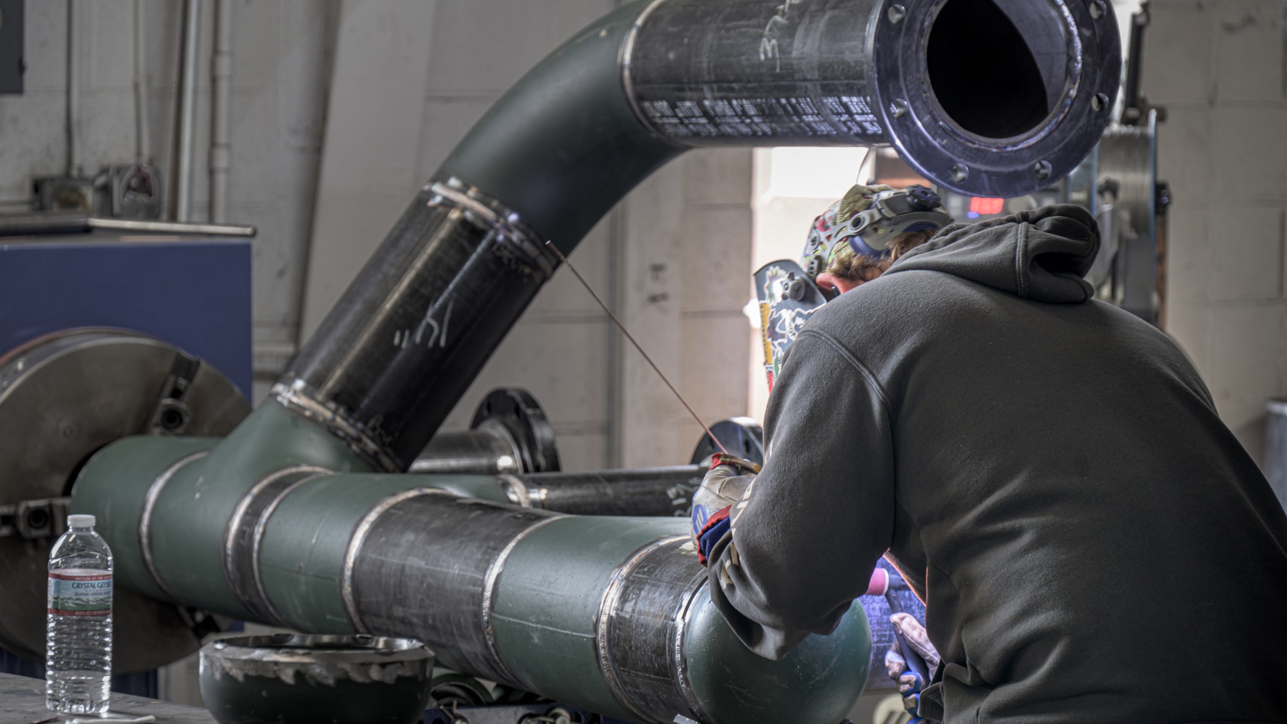 A welder works on a pipe for a large heating unit